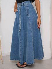 High-waisted A-line denim skirt in Dusty Blue with a tie belt and pockets.