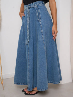 High-waisted A-line denim skirt in Dusty Blue with a tie belt and pockets.