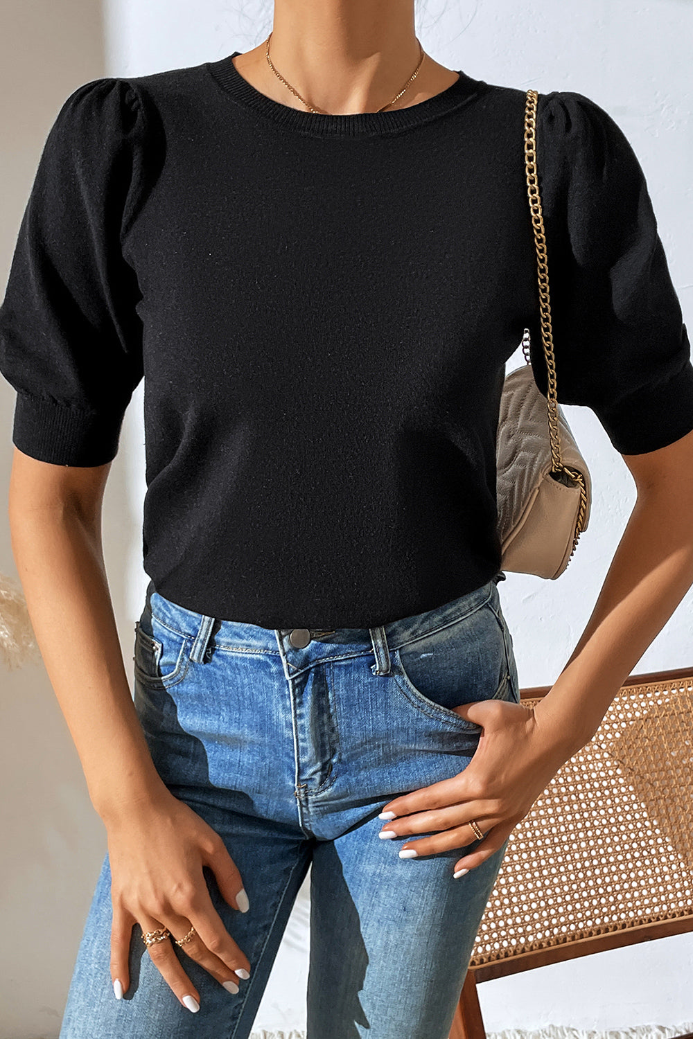 Black knit sweater with puff sleeves and crew neck, styled with jeans.
