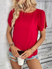 Red blouse with slit sleeves and a round neckline, styled with denim shorts.