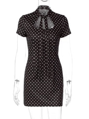 Black polka dot mini dress with short sleeves and a tie-neck cut-out detail.