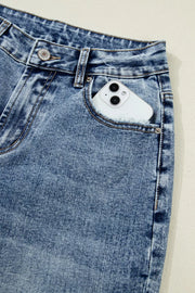 Cuffed mid-rise relaxed fit jeans in distressed blue denim with a phone in the pocket.