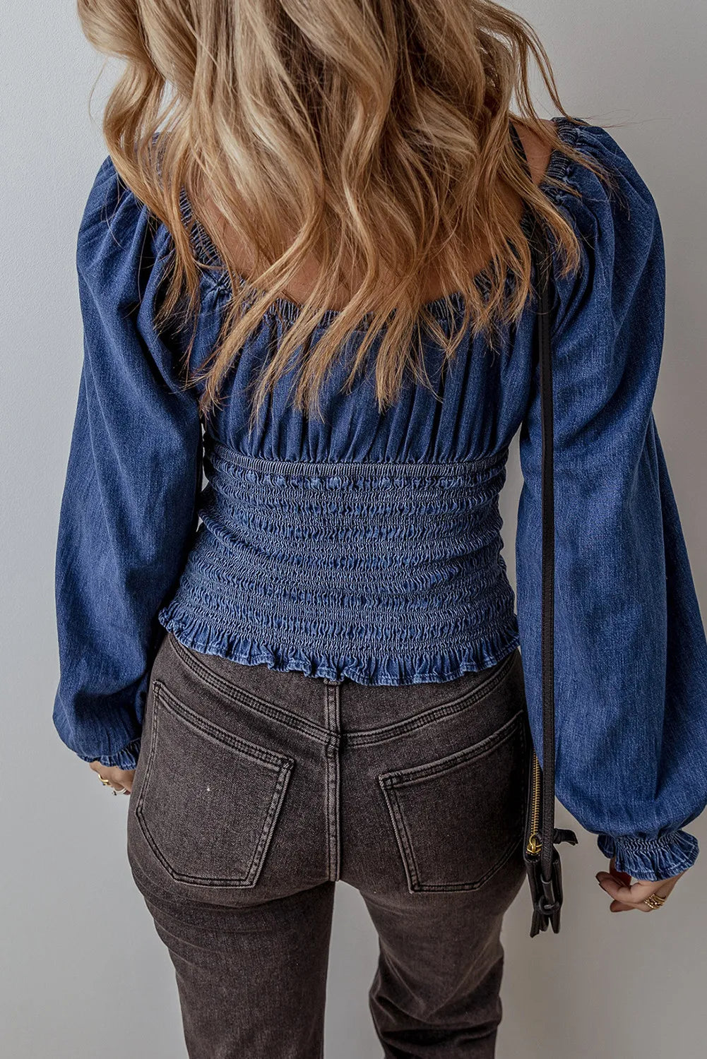 Denim corset bodice blouse with smocked waist and blouson sleeves in medium wash cotton.