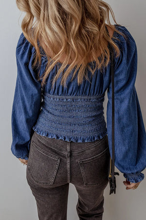 Denim corset bodice blouse with smocked waist and blouson sleeves in medium wash cotton.
