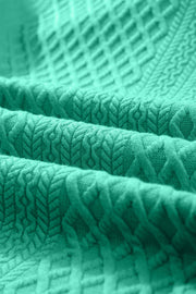 Turquoise textured trapeze dress with ruffle sleeves and a subtle geometric pattern.