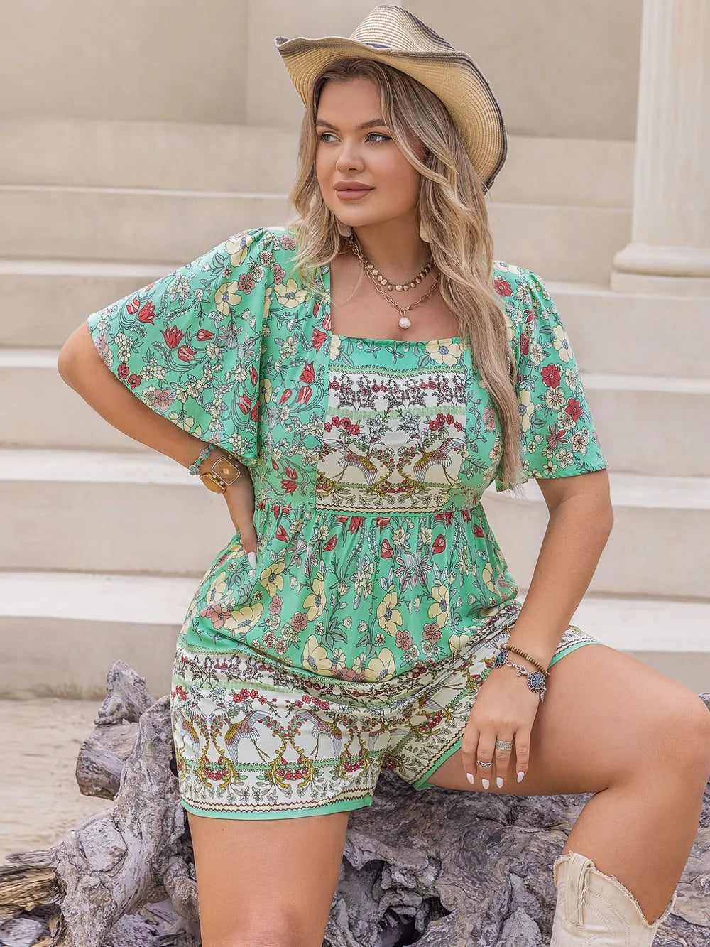 Plus-size green floral romper with square neck, short sleeves, and cinched waist.