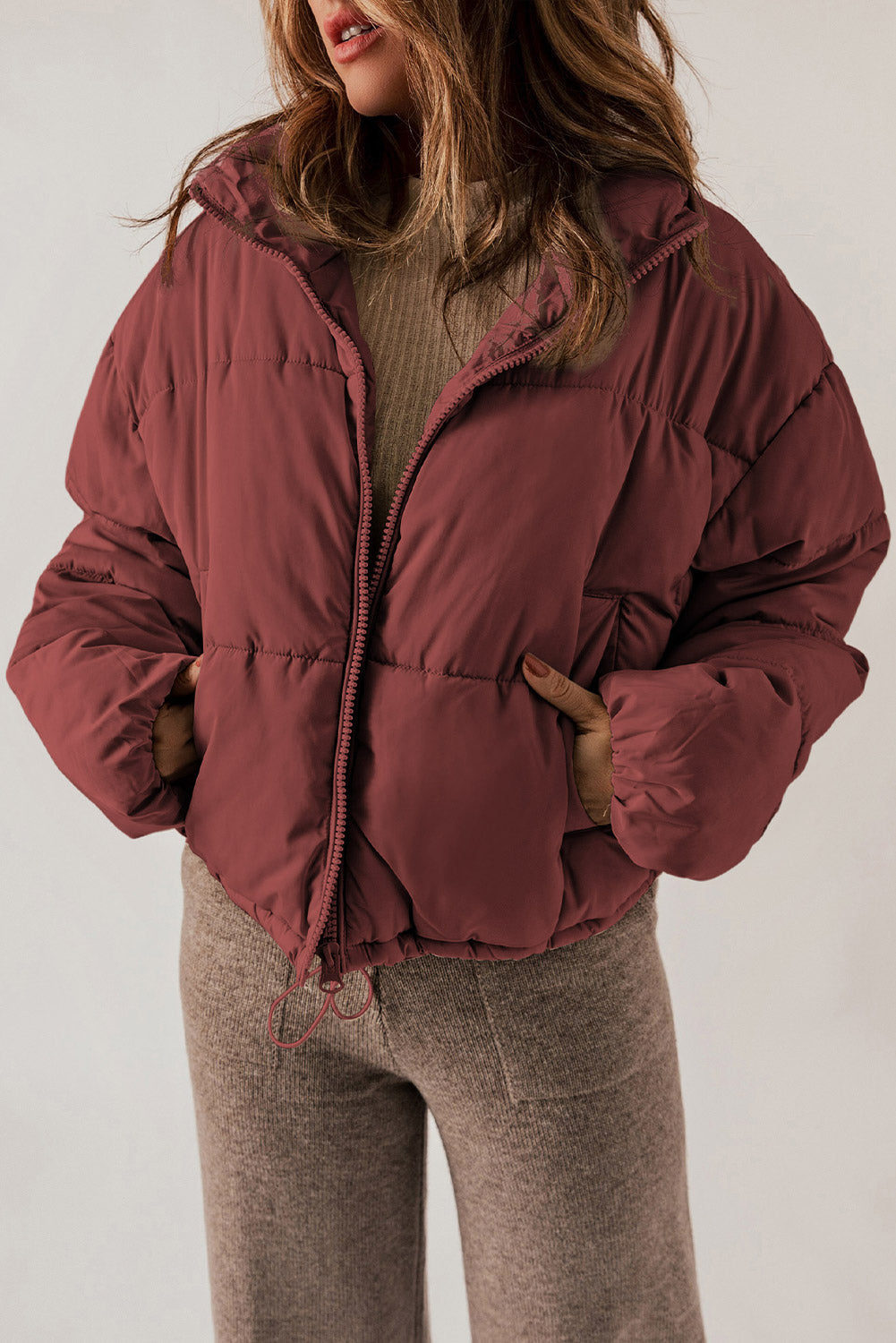 Cropped puffer jacket in brick red with a hooded collar and drawstring hem.