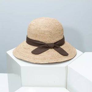 Chic wheat straw sun hat with brown bow detail and wide brim.
