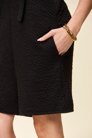 Black textured bib short romper with pocket detail