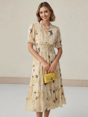 Beige butterfly print midi dress with smocked waist, V-neck, short sleeves, and tiered skirt.