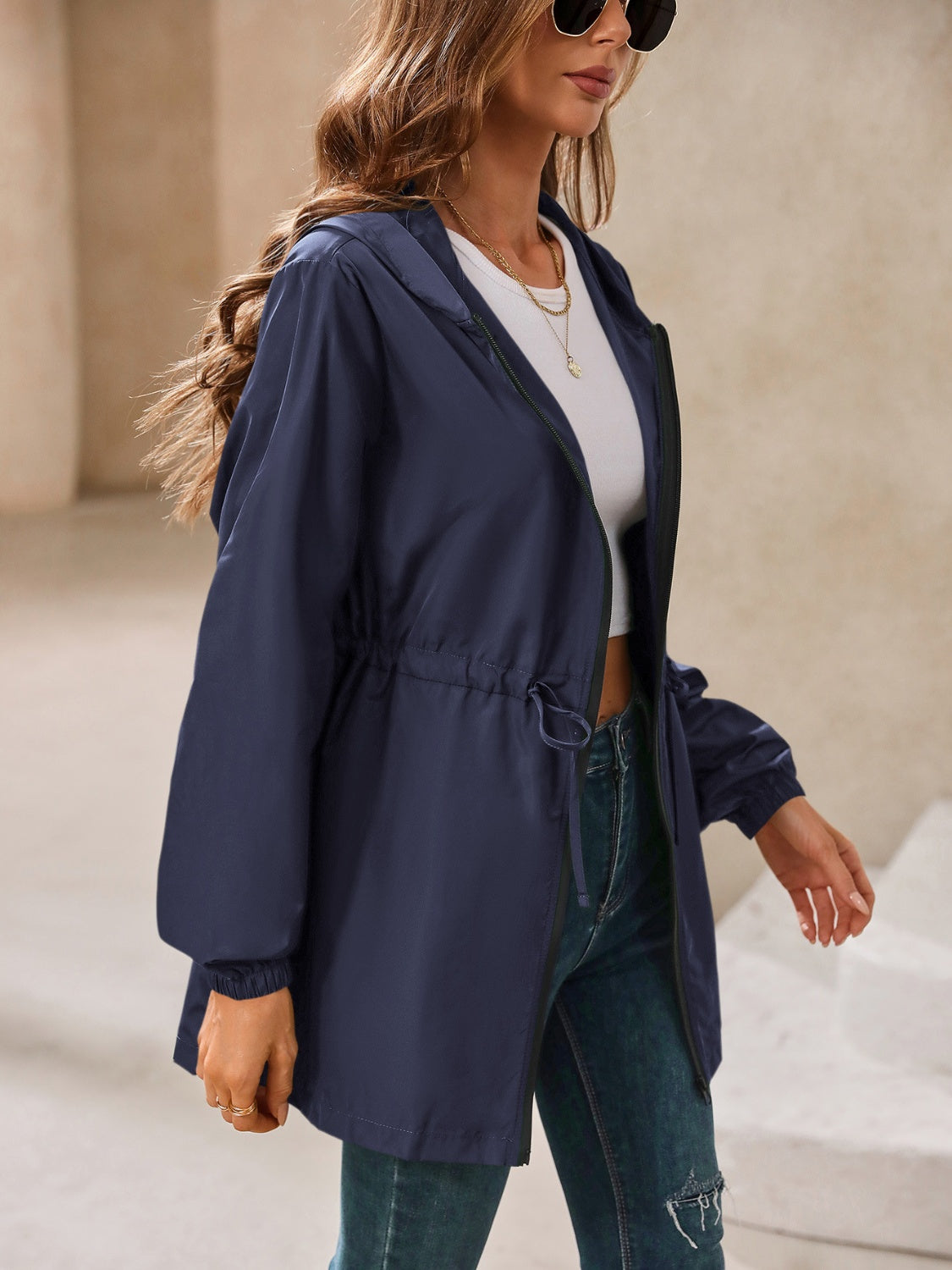 Navy hooded jacket with cinched waistline and drawstring detail.