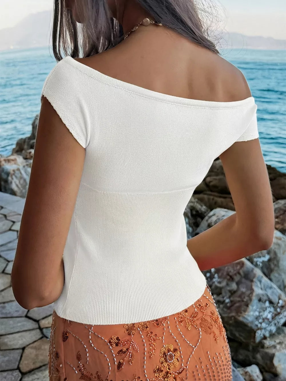 White off-shoulder knit top with short sleeves and a ribbed waistband.
