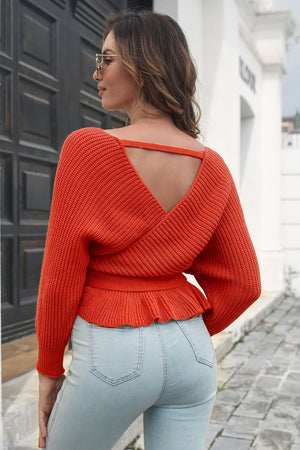 Orange-red acrylic wrap sweater with open back detail and peplum hem