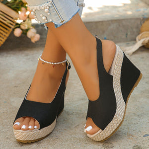 Black woven espadrille wedge sandals with peep toe and slingback strap.
