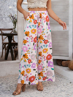 Geometric print wide-leg trousers with drawstring waist and pockets in multicolor floral pattern.