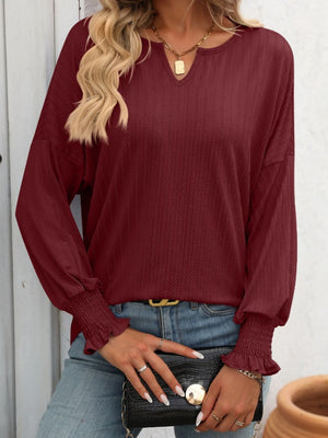 Burgundy textured blouson top with v-neck and smocked cuffs