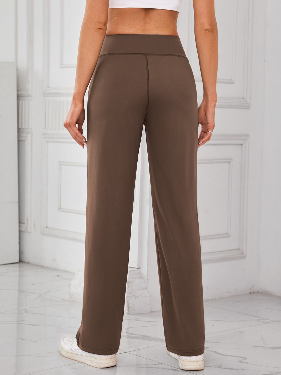 Brown wide-leg lounge trousers with a high waist and straight leg, styled with sneakers.