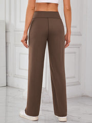Brown wide-leg lounge trousers with a high waist and straight leg, styled with sneakers.