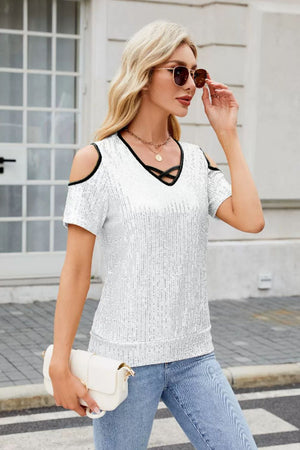White sequin cold shoulder blouse with black trim and crisscross neckline.