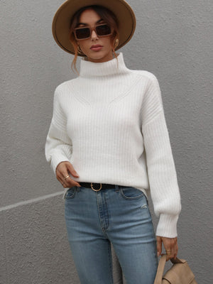 White ribbed knit turtleneck sweater with voluminous sleeves and a V-stitch detail at the neckline.