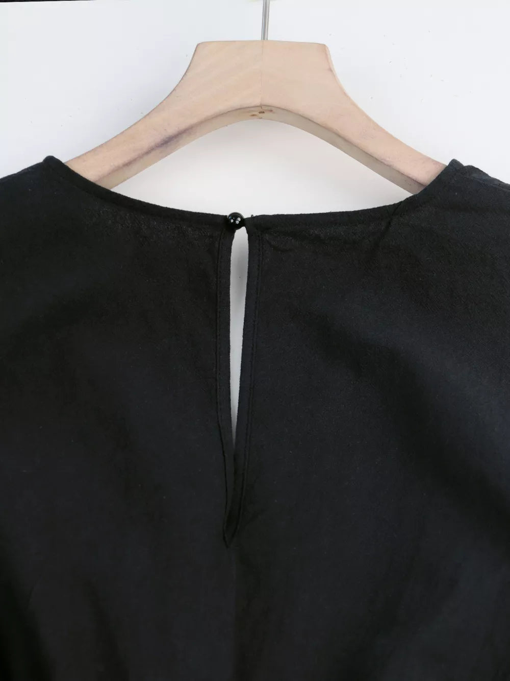 Black cotton romper with button-down detail and keyhole back.