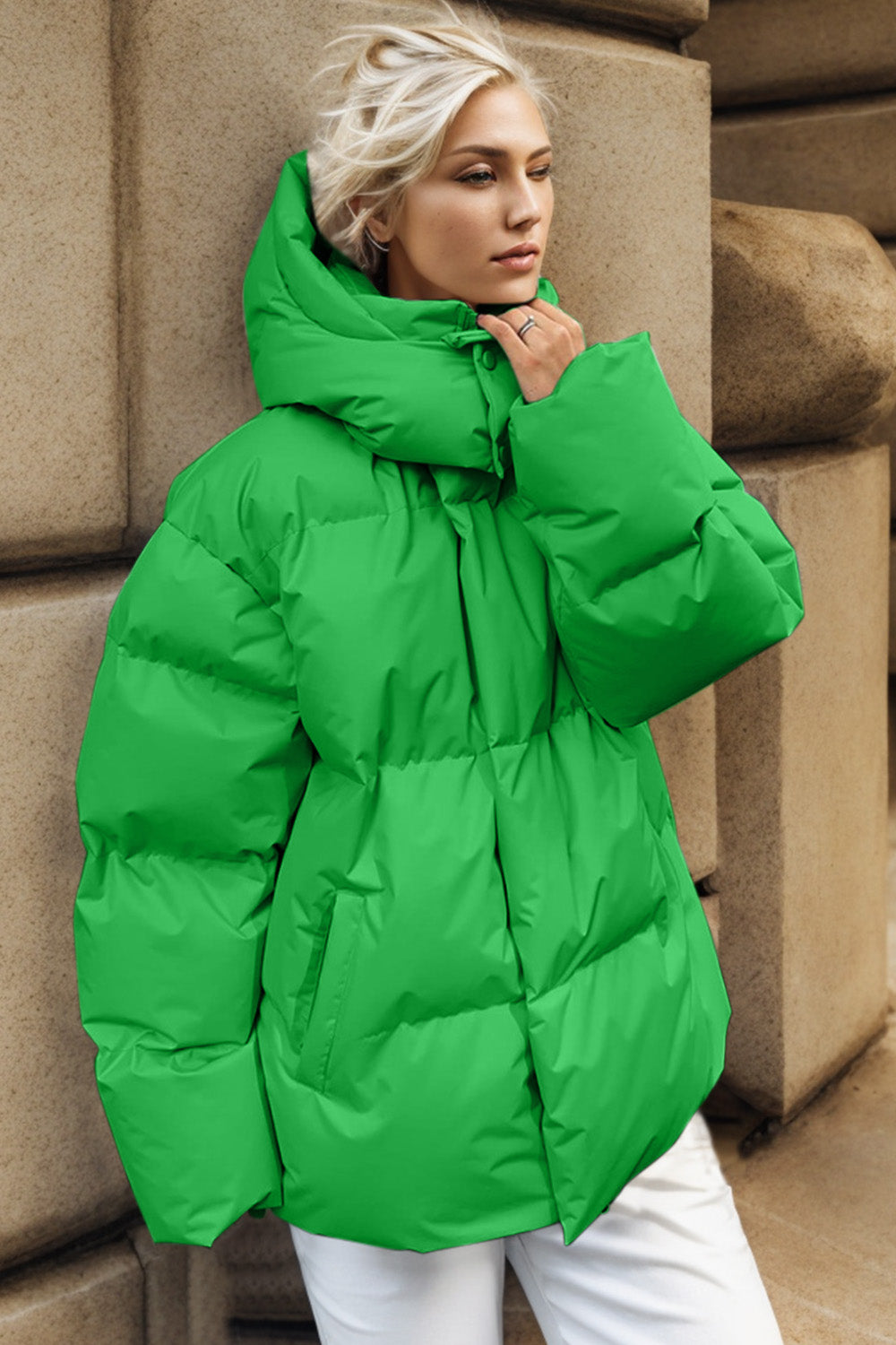 Green oversized puffer jacket with hood and cinched waist detail.