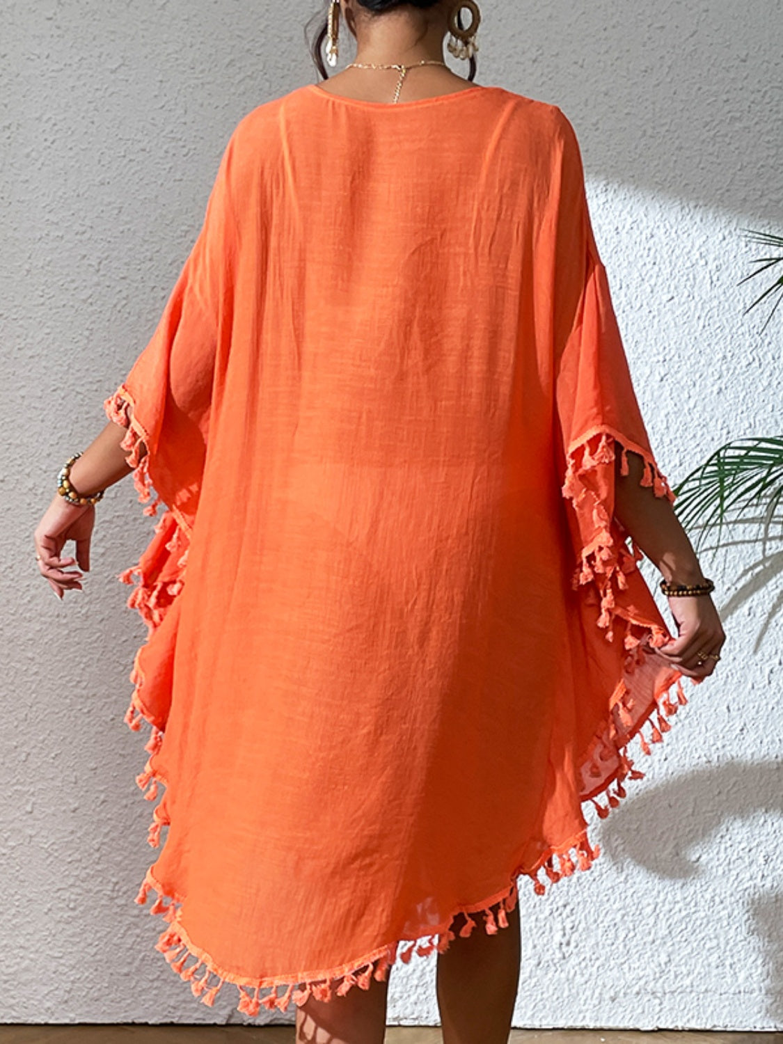 Orange kaftan dress with crochet yoke and tassel trim, shown from the back.