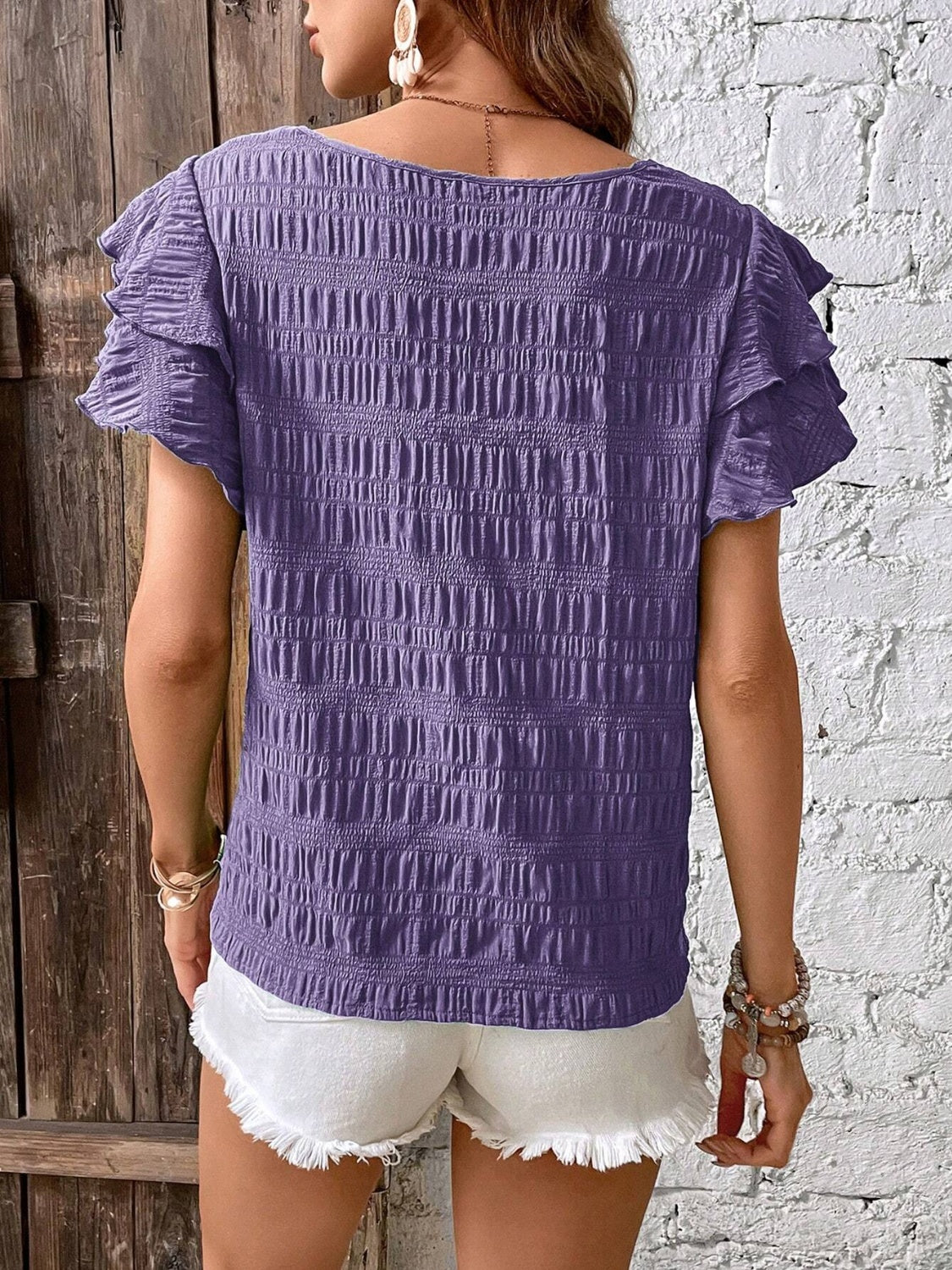 Purple textured smocked blouse with ruffle sleeves.