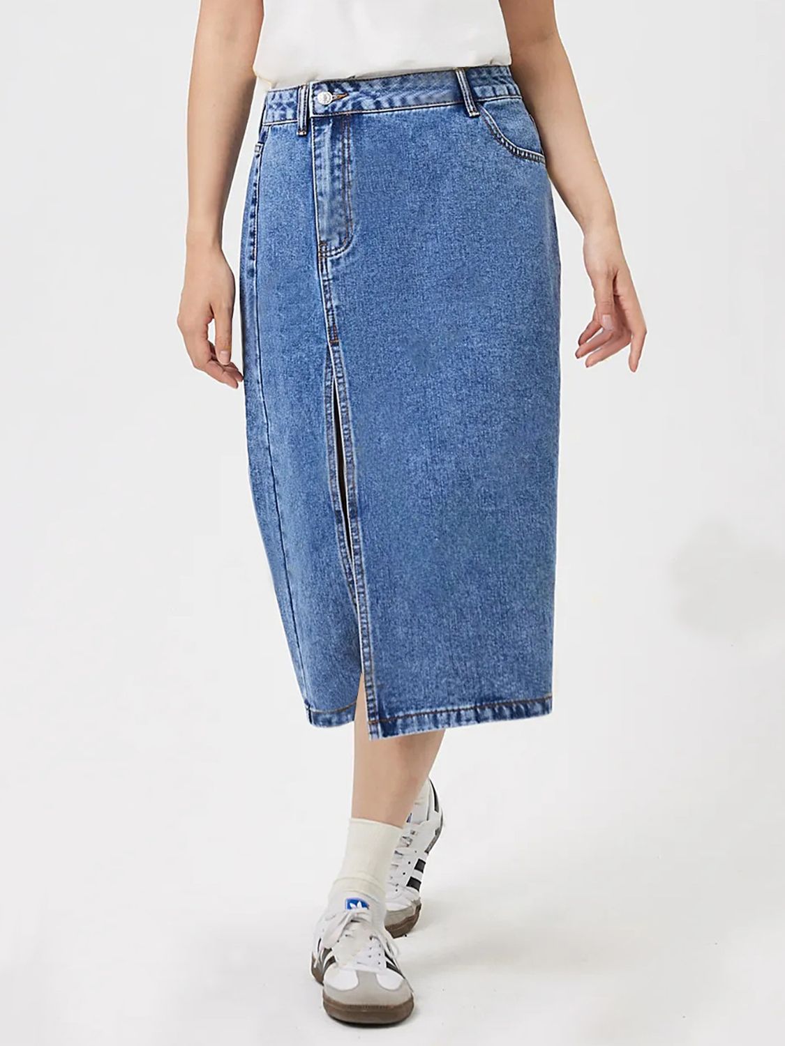 High-slit denim midi skirt in medium wash cotton, styled with sneakers.