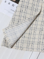 Beige plaid mini skirt with ruched detail and belt, showing fabric texture.
