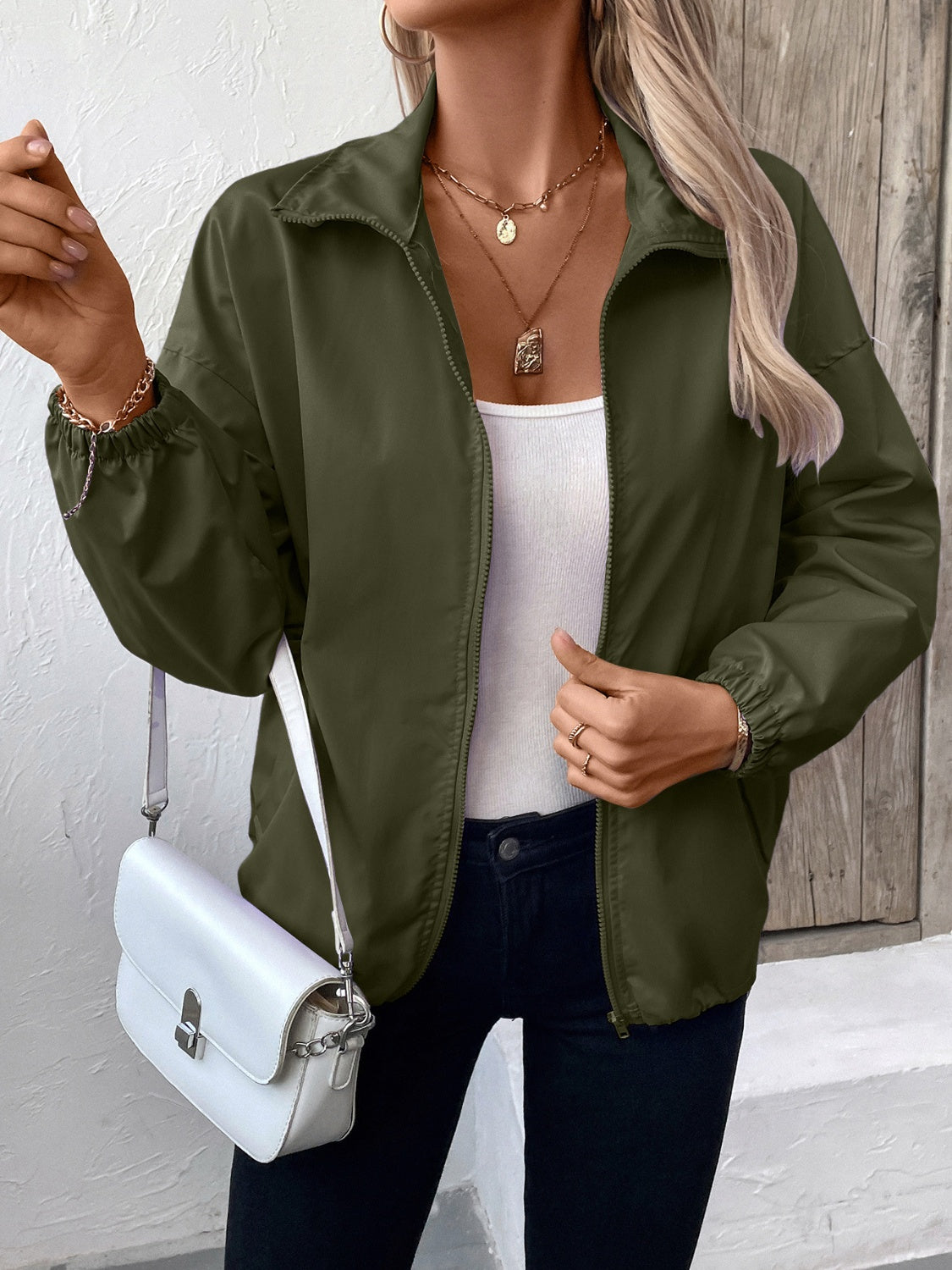 Army green nylon bomber jacket with drawstring hem and zippered front.