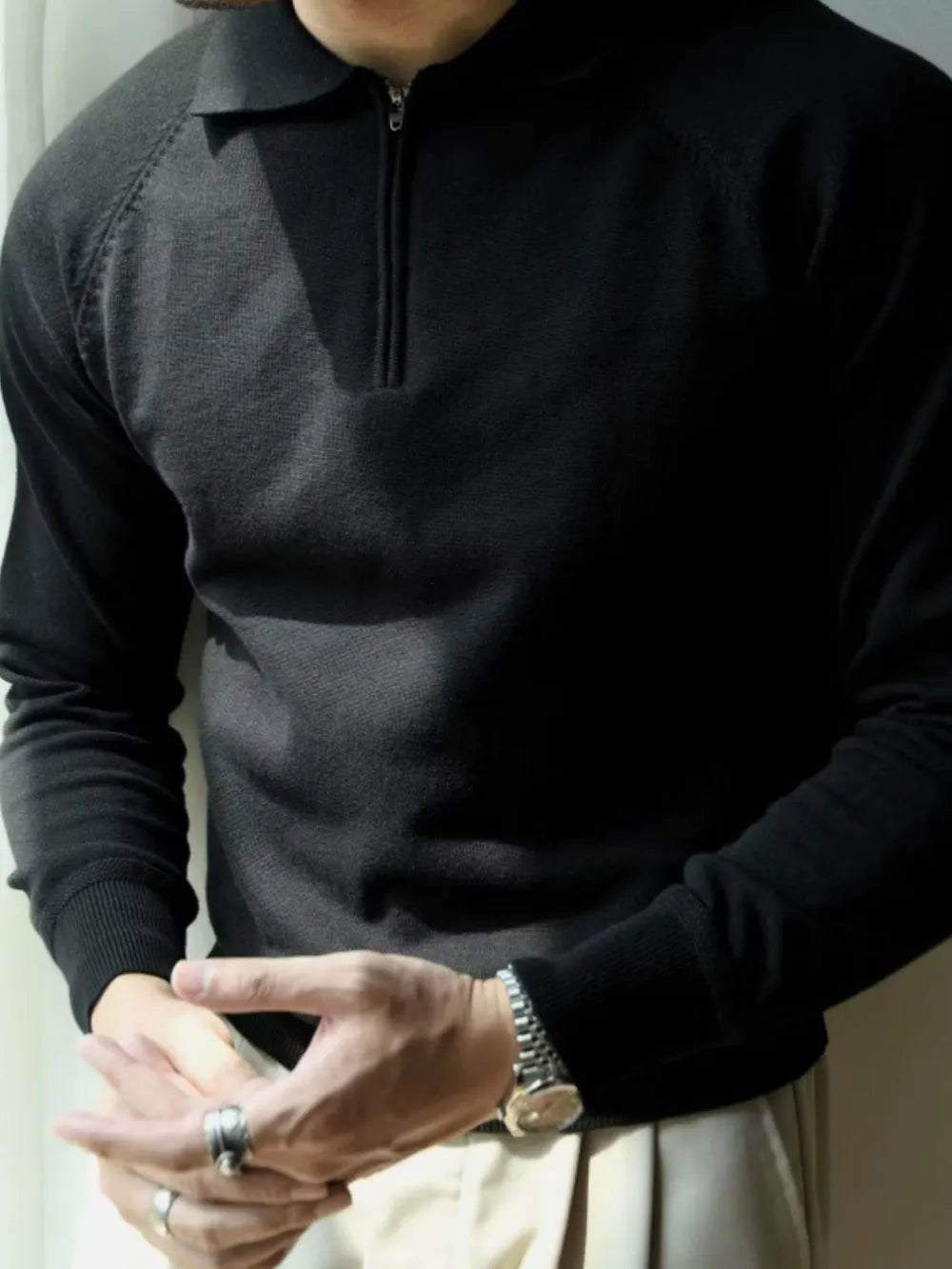 Black knit polo with zip-through neckline and raglan sleeves.