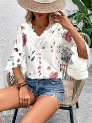 White floral print blouse with lace trim and bell sleeves.