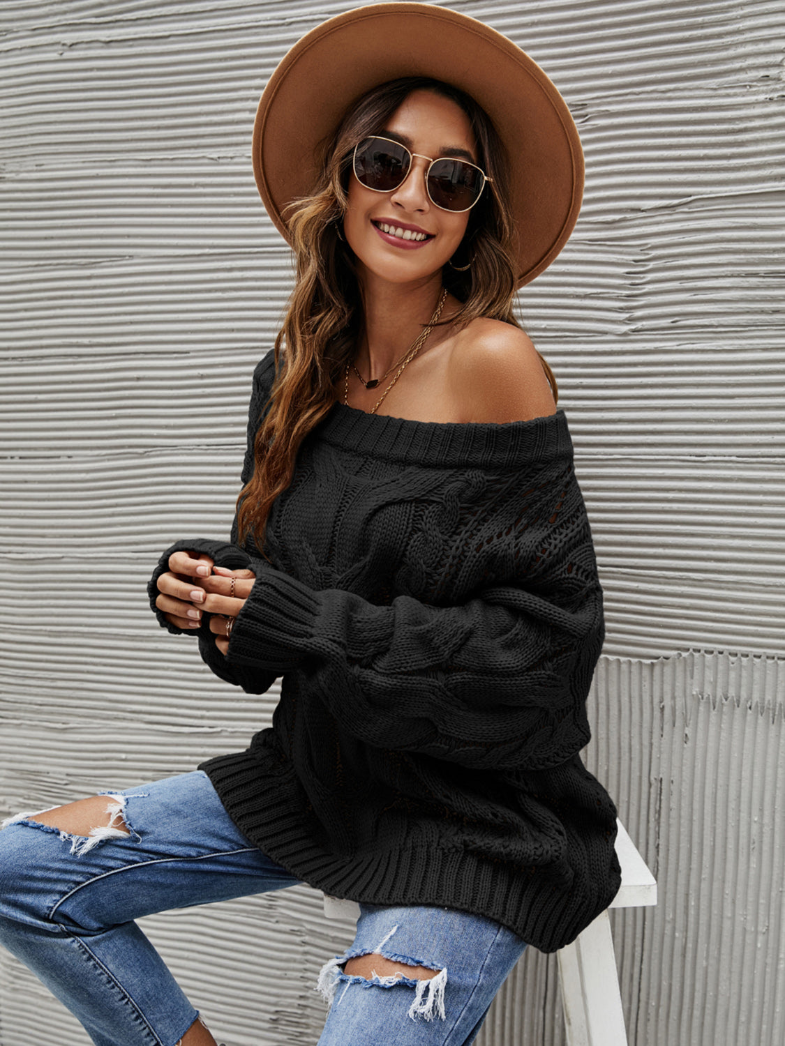 Black cable knit off-shoulder slouch sweater with a relaxed fit.