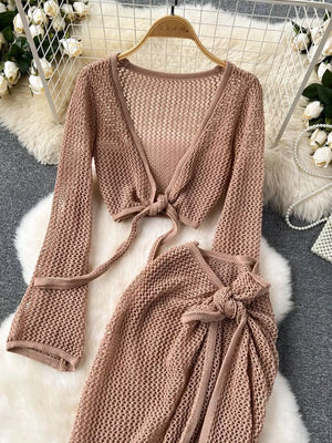 Tied crop top with V-neck and long sleeves, paired with a high slit wrap skirt, both in a crochet knit.