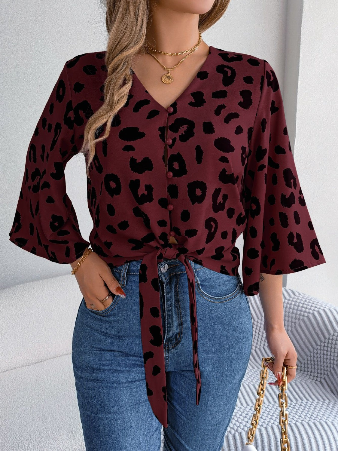 Burgundy leopard print tie-front blouse with button detail and bell sleeves.