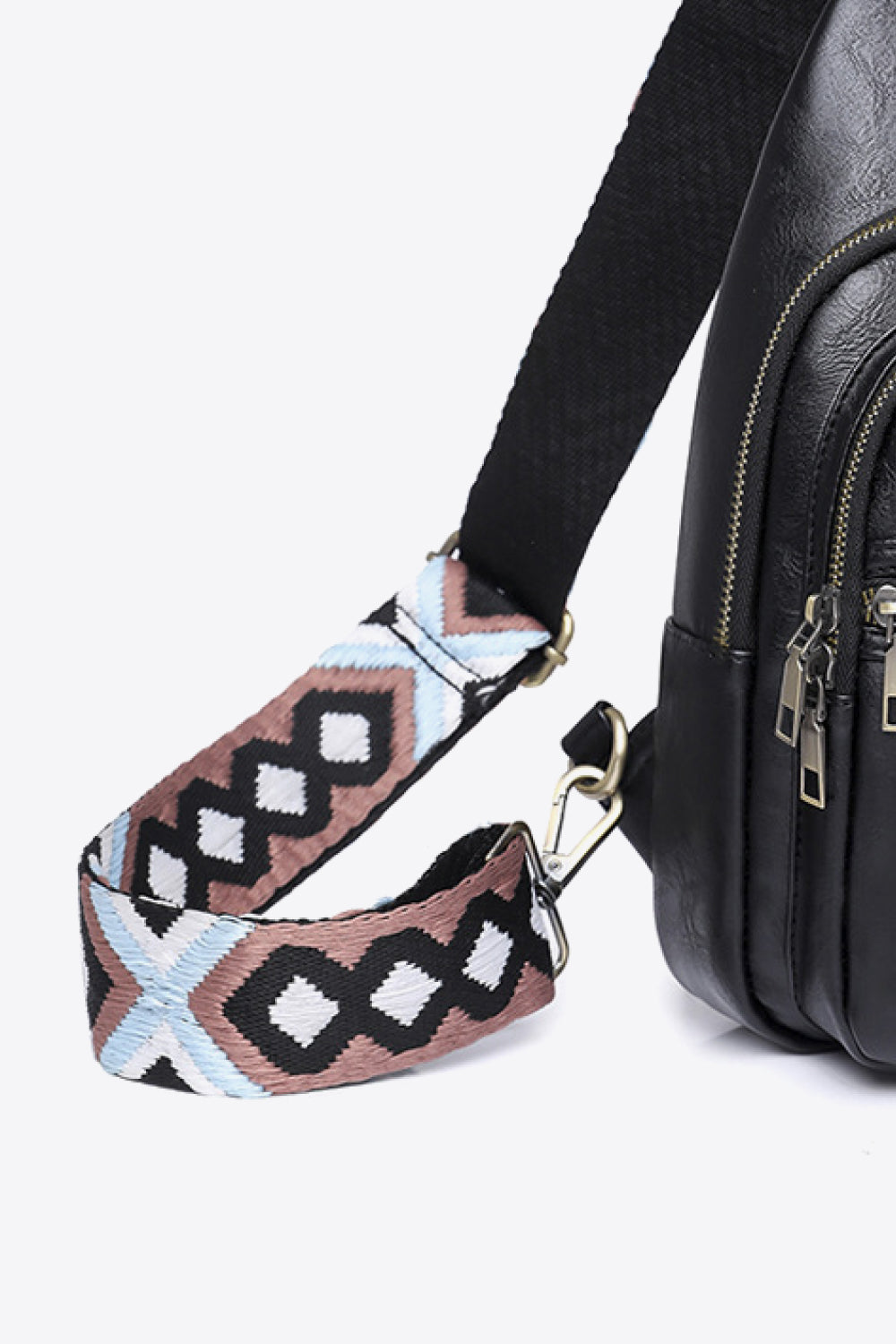Black crossbody bag with geometric patterned strap and silver hardware.