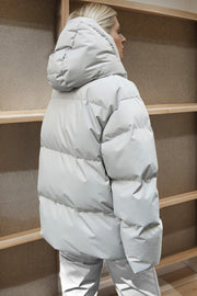 Light gray oversized puffer jacket with hood and horizontal quilting.
