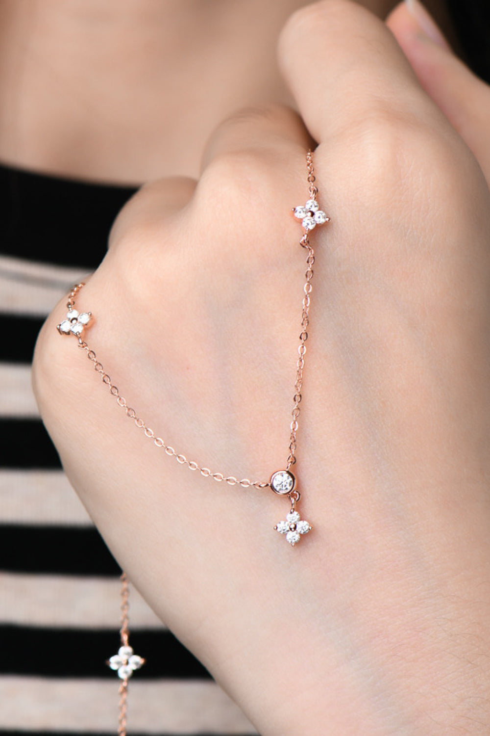 Rose gold necklace with diamond cluster clover charms and a central diamond accent.
