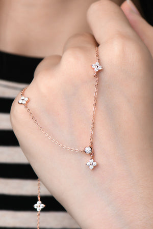 Rose gold necklace with diamond cluster clover charms and a central diamond accent.