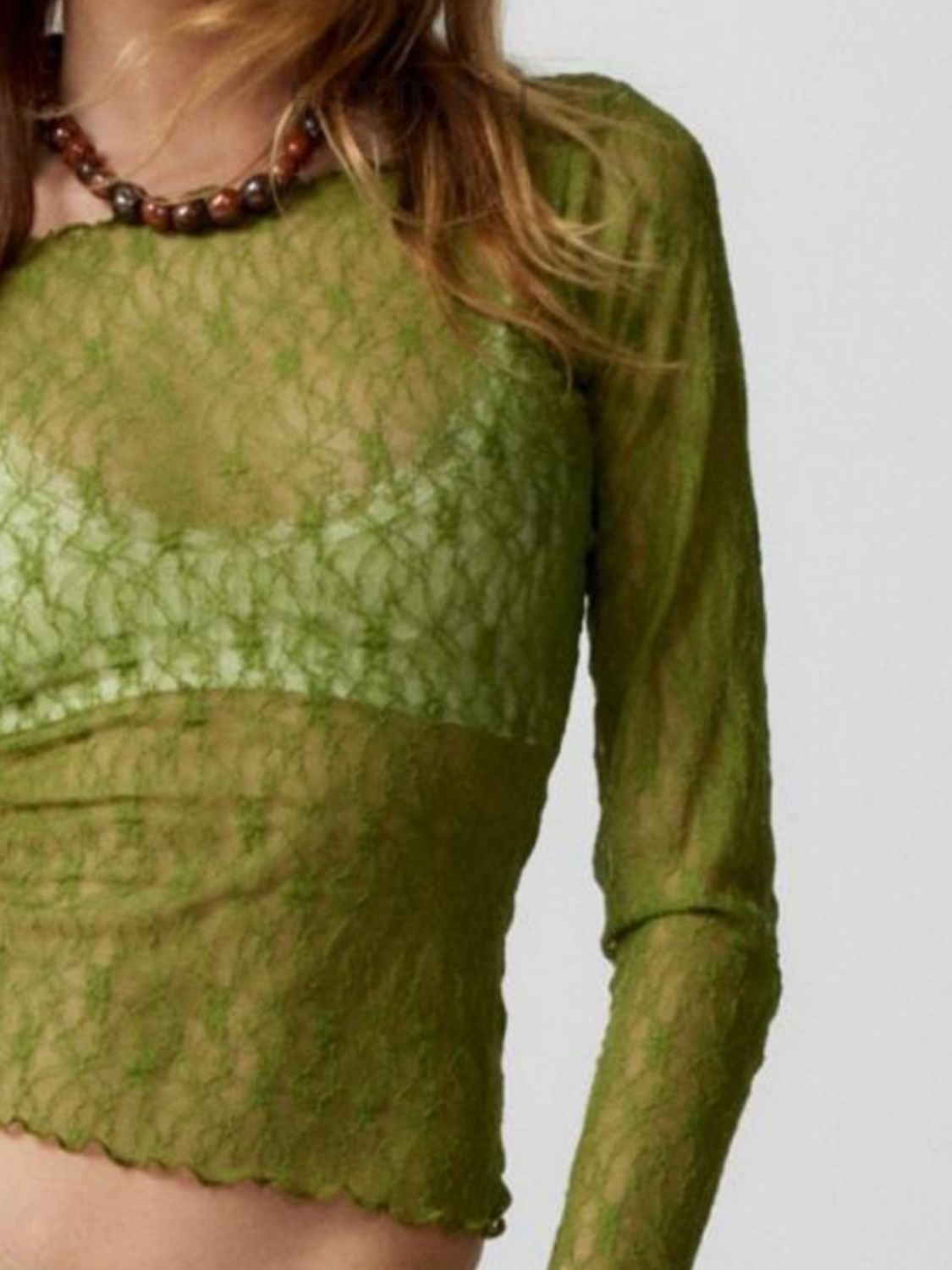 Olive green lace blouse with scalloped hem and long sleeves, worn with a green bralette.