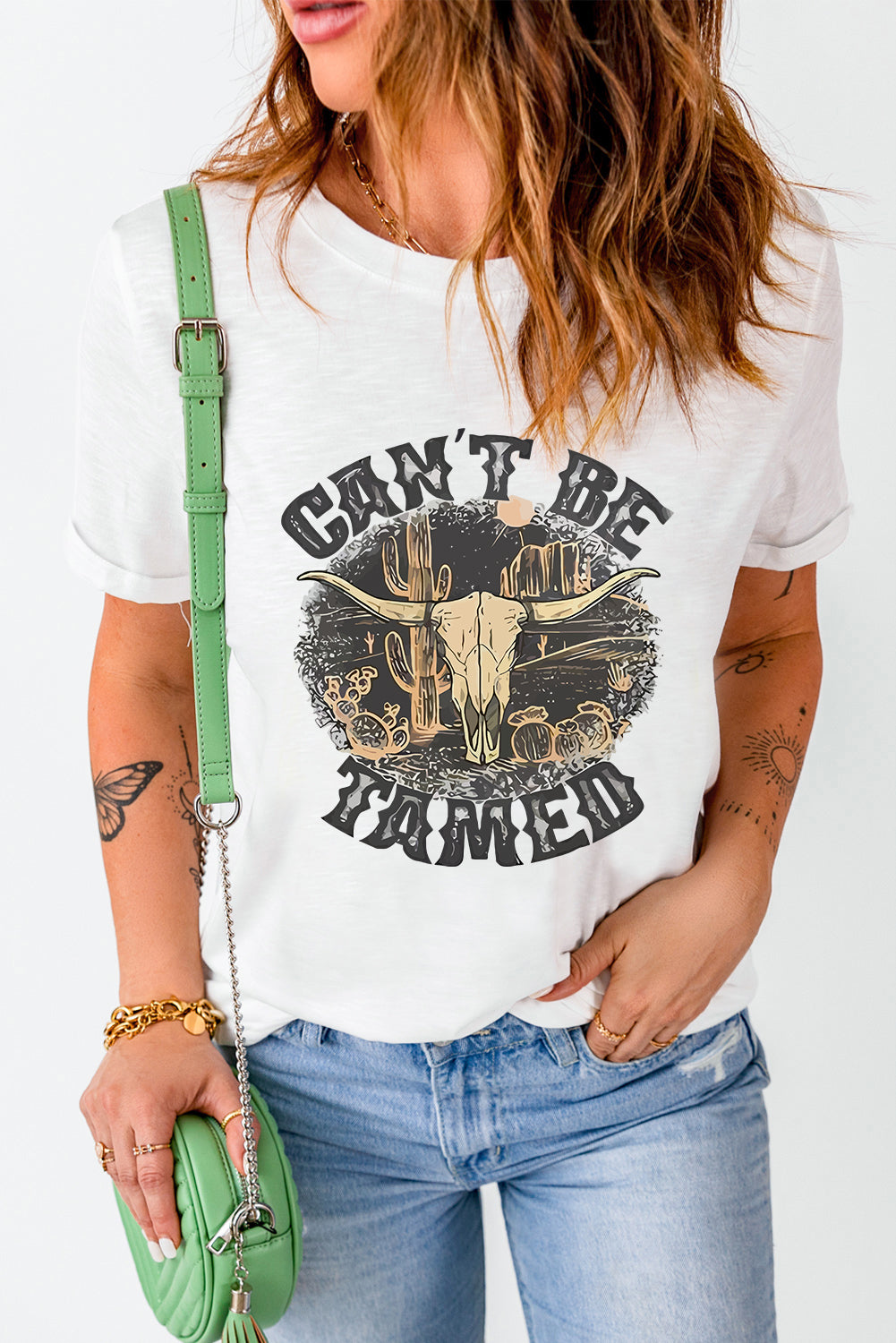 White cotton blend graphic tee with "Can't Be Tamed" text and bull skull desert graphic