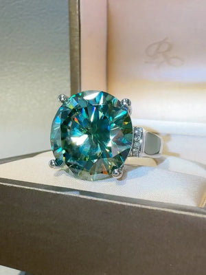 Prismatic teal statement ring with a large faceted gemstone and small accent stones.