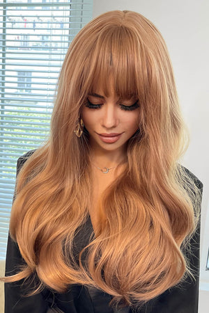 Strawberry blonde wig with bangs and loose waves, styled with a black top.