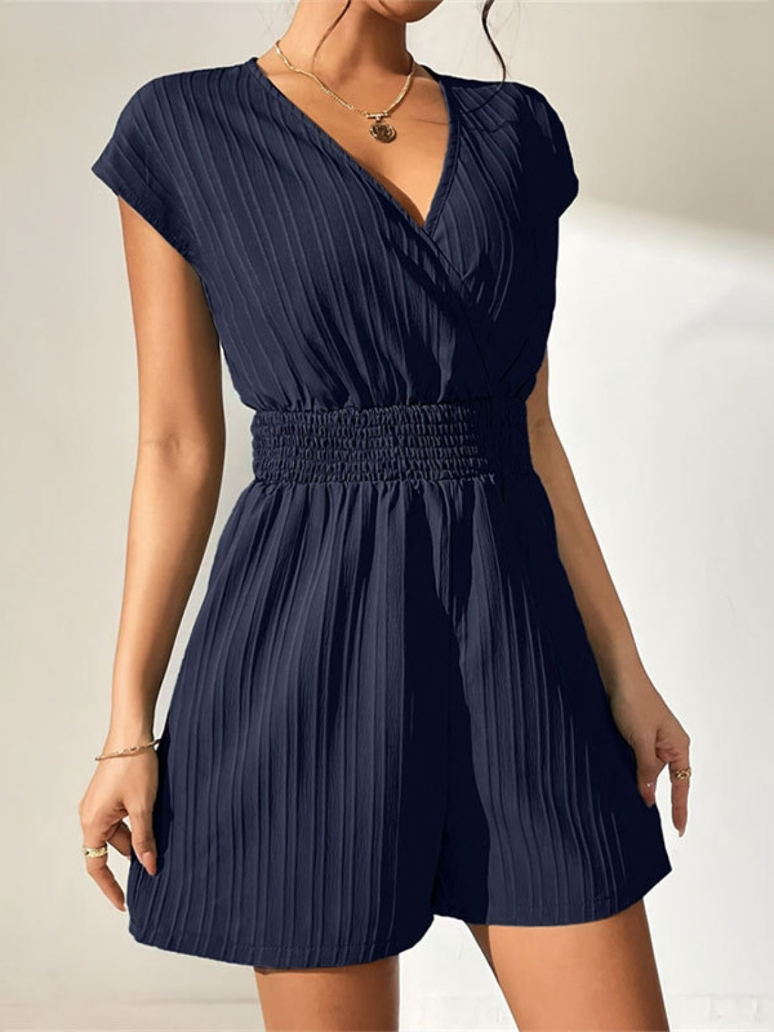 Navy textured wrap romper with V-neck, short sleeves, and smocked waist.