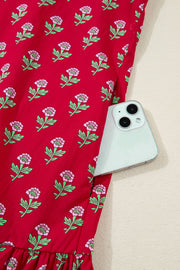 Red floral mini dress with pink flowers, green leaves, and a pocket holding a phone.