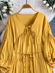 Yellow bohemian maxi dress with balloon sleeves, V-neck tie detail, and cinched waist.