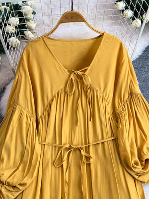 Yellow bohemian maxi dress with balloon sleeves, V-neck tie detail, and cinched waist.