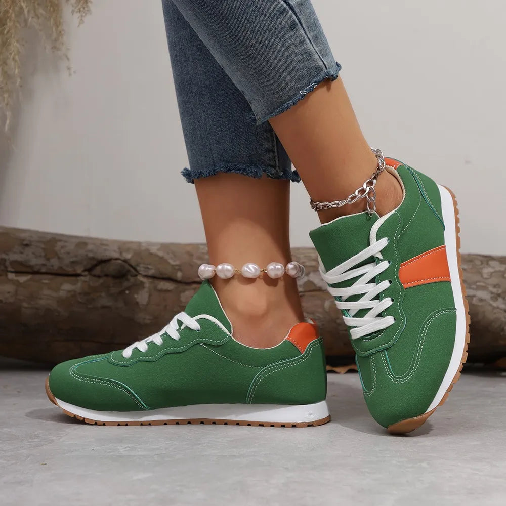 Green suede and canvas sneakers with orange accents and white laces.