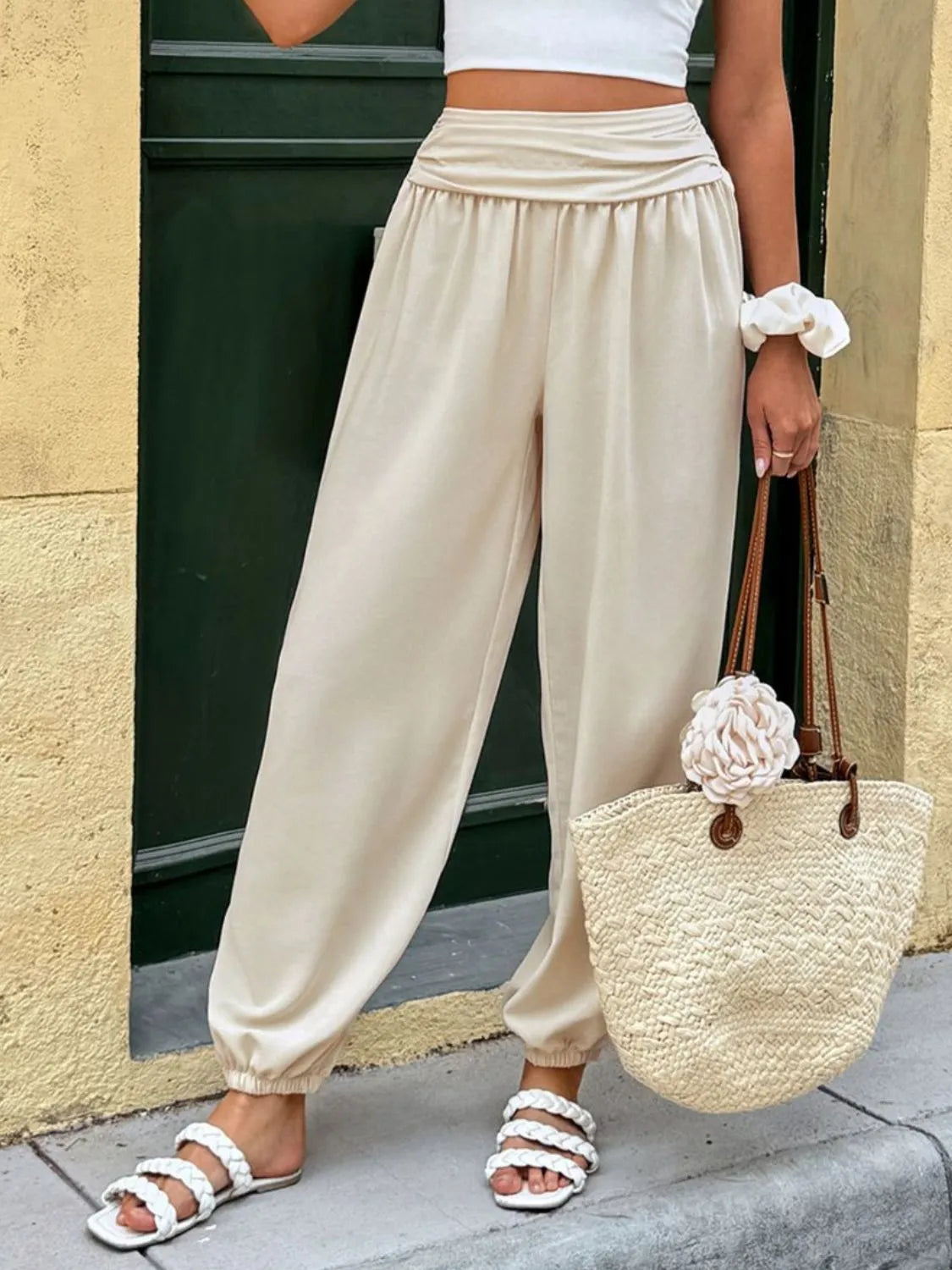 Cream ruched waistline balloon trousers with elastic cuffs, styled with white sandals and a straw bag.